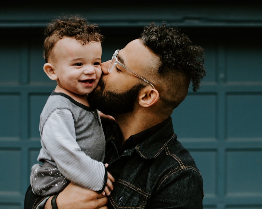 Papá cargando y dando un beso a su hijo sonriente